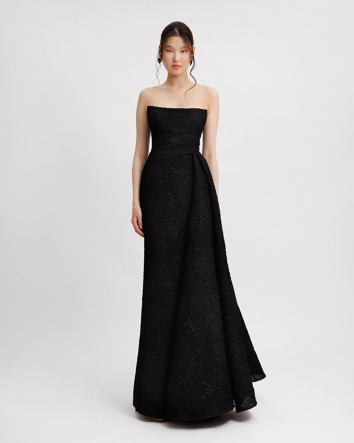 A strapless black dress with a one-sided draped skirt.