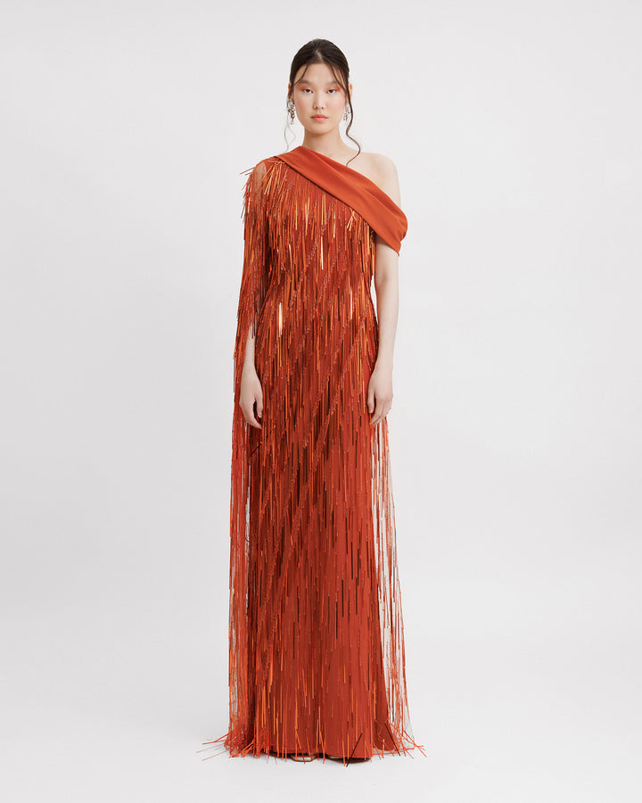 A fully beaded fringes orange dress featuring a one-shoulder crepe fold-over, and a single floor-length sleeve.