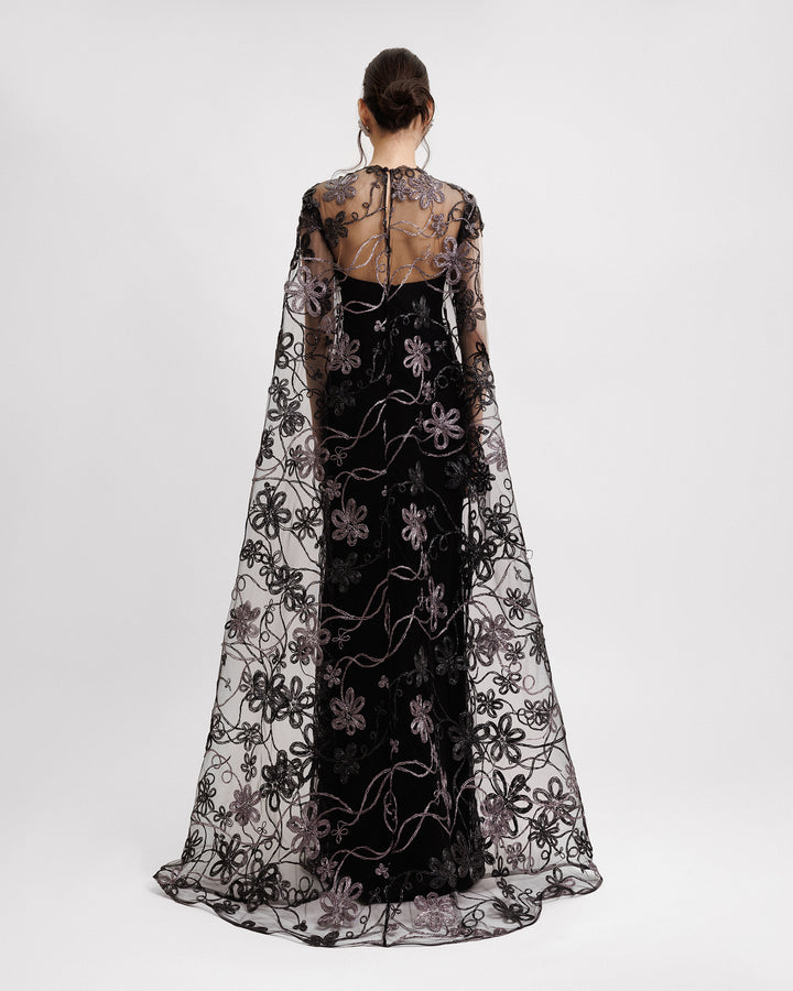 The back of a long floral embroidered tulle evening dress in black with a cape-like back.