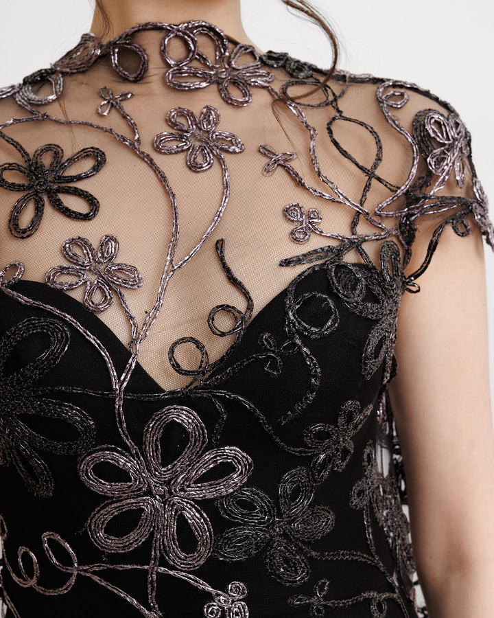 A close-up of a long floral embroidered black evening dress.