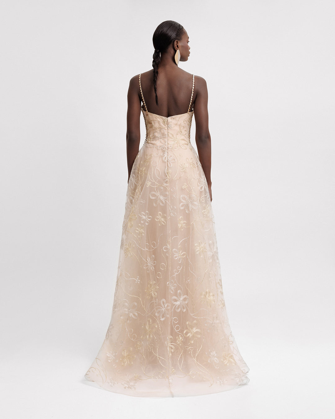 The back of a long champagne evening dress with a flared embroidered skirt.