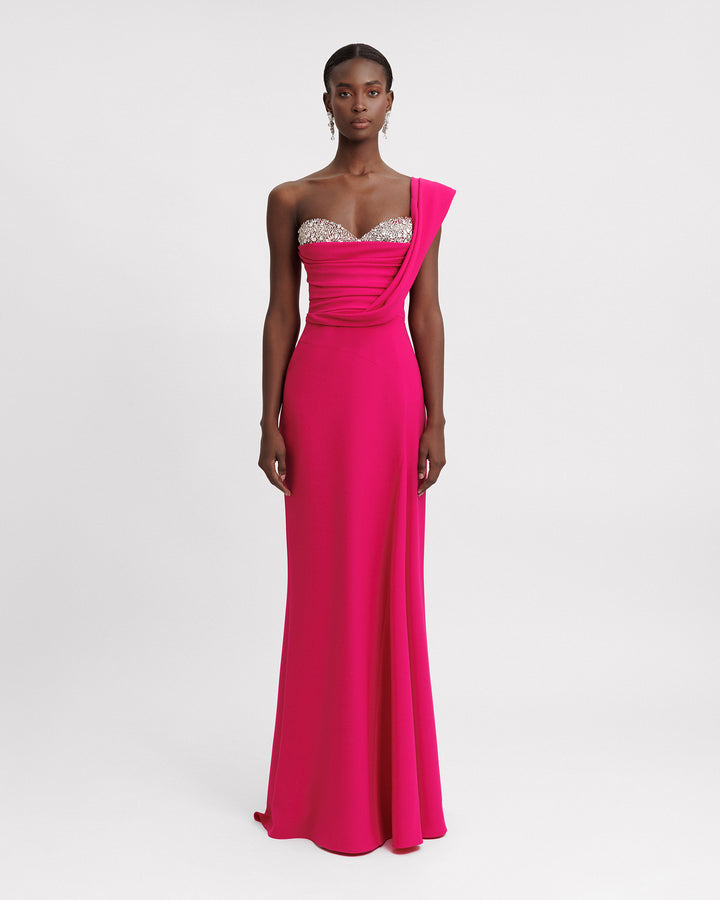 A one-shoulder fuchsia evening dress featuring a draped corset and beaded heart shaped neckline.