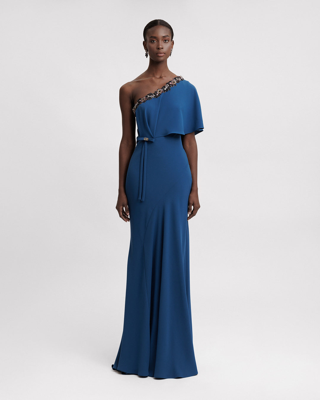 A long evening dress featuring a beaded one-shoulder cut, and a bow at the side waist.