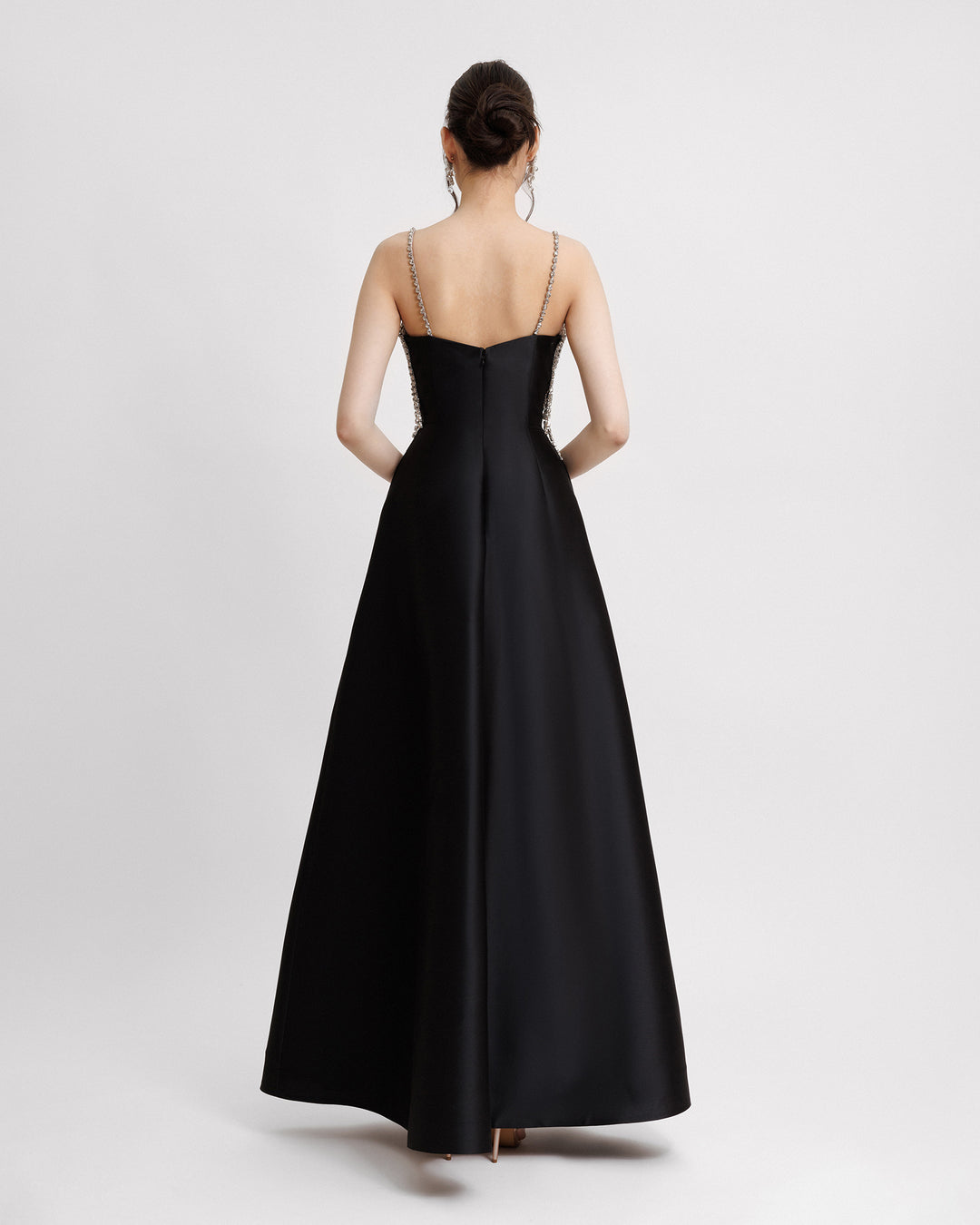 The back of a wide skirt long black evening dress in mikado fabric.