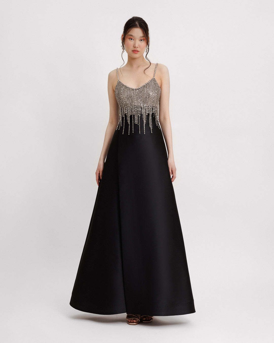 A long black evening dress featuring a beaded tassels bodice on a wide mikado skirt.