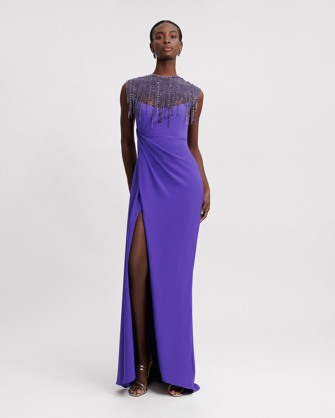 A slim-cut purple evening dress with a beaded tassels collar, draping on the waist, and a slit on the side.