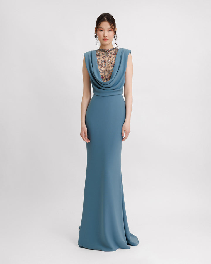 A slim-cut blue evening dress featuring a beaded cowl-neckline and structured shoulders.