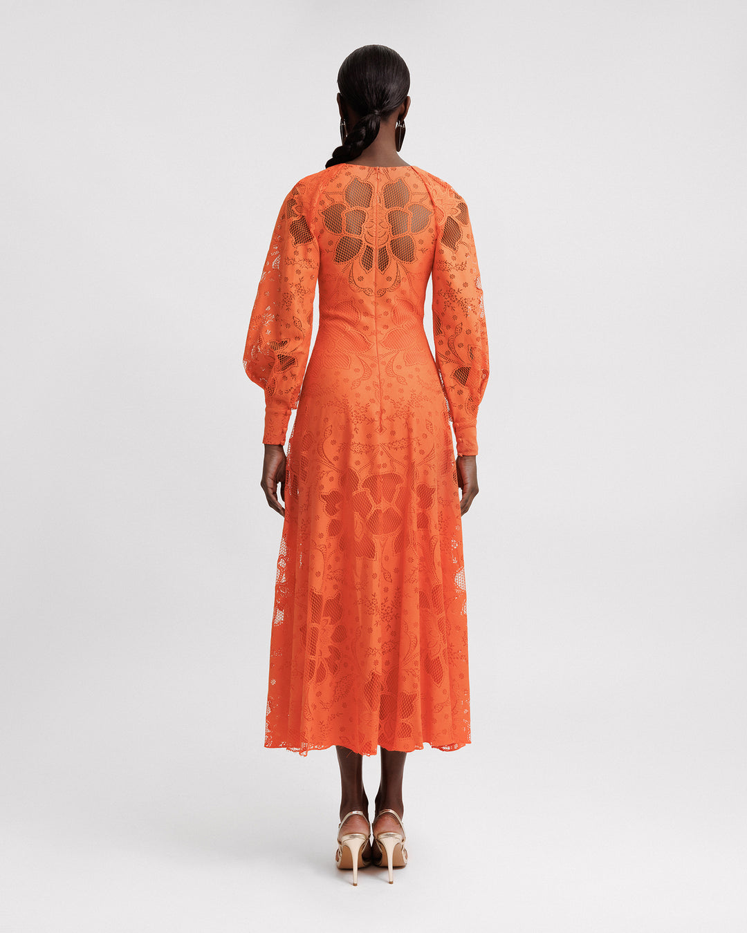 The back of an orange lace midi dress with draped bishop sleeves.