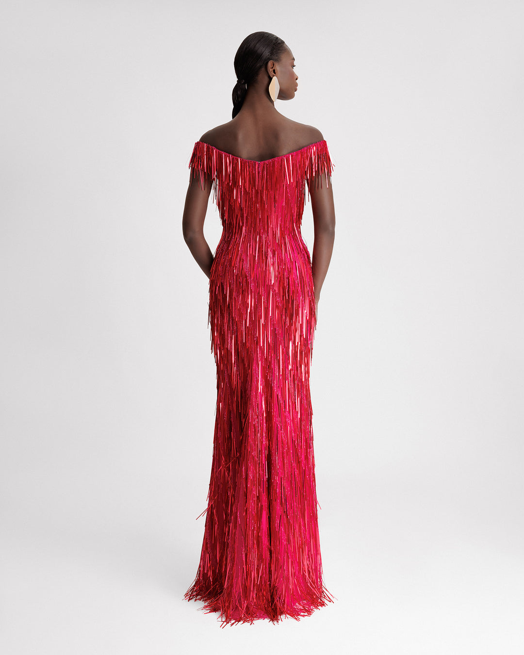 The back of an off-the-shoulders, slim-cut, fully beaded fringes evening dress in fuchsia color.