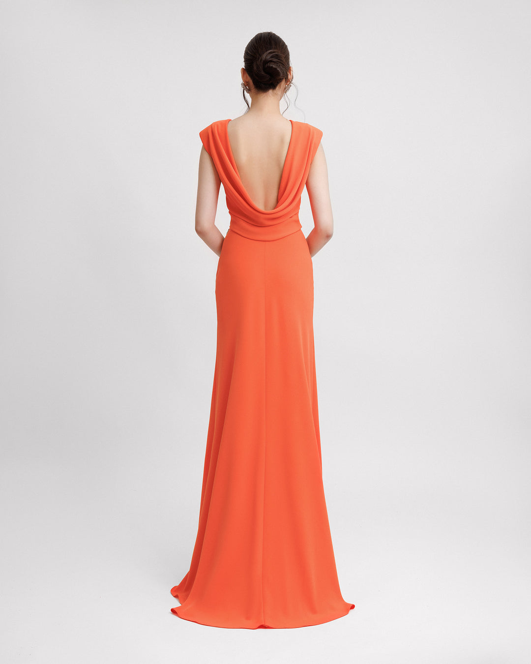 The back of a slim-cut long orange evening dress with a draped low open back.