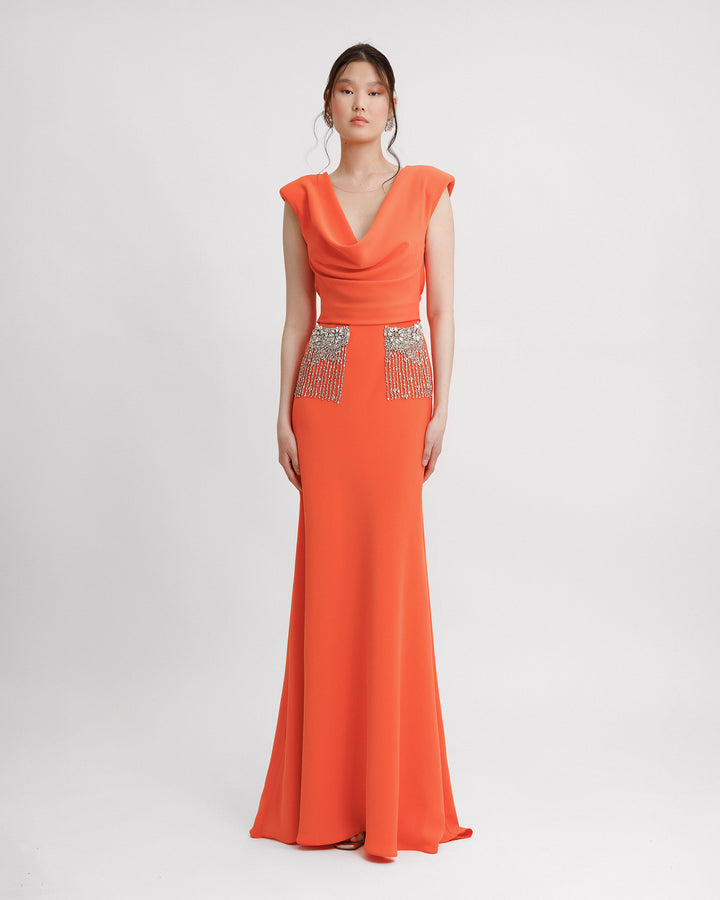 A slim-cut long orange evening dress with a draped cowl neckline, and beaded pockets.