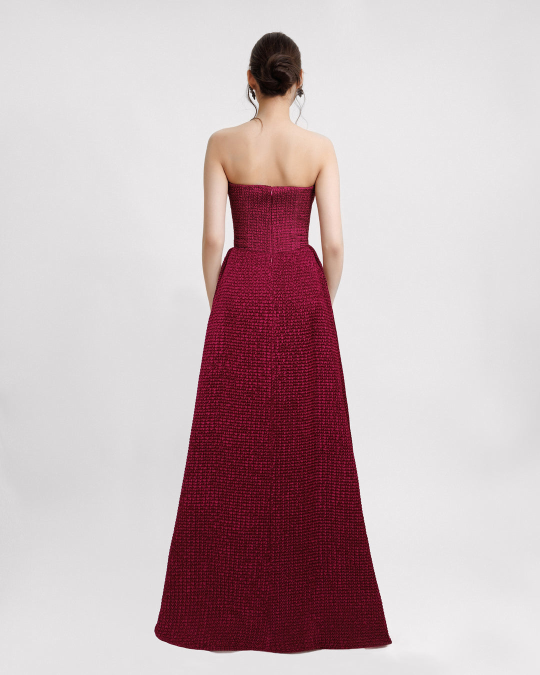 The back of a dark fuchsia strapless evening dress with a plunging neckline and draping on the waistline.