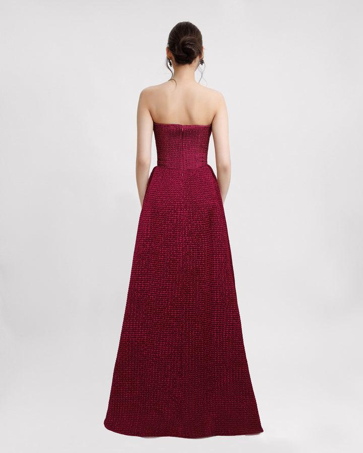 The back of a dark fuchsia strapless evening dress with a plunging neckline and draping on the waistline.