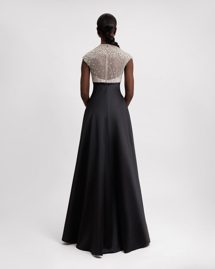 The back of a long black evening dress featuring a beaded silver corset and a wide mikado skirt with pockets.