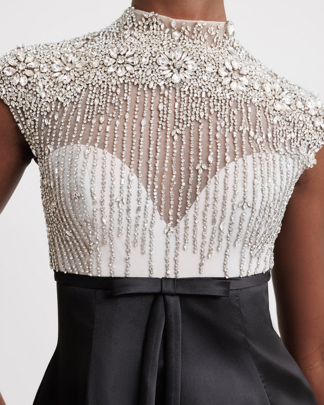 A close-up of a long black evening dress featuring a beaded silver corset and a wide mikado skirt.