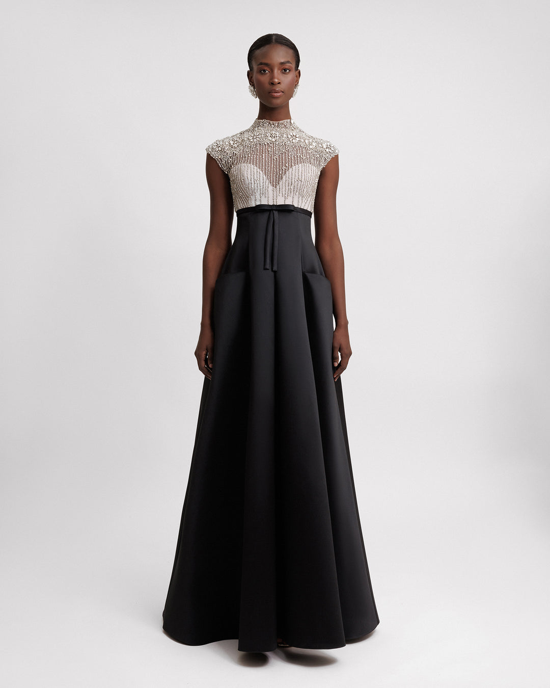 A long black evening dress featuring a beaded silver corset and a wide mikado skirt with pockets.