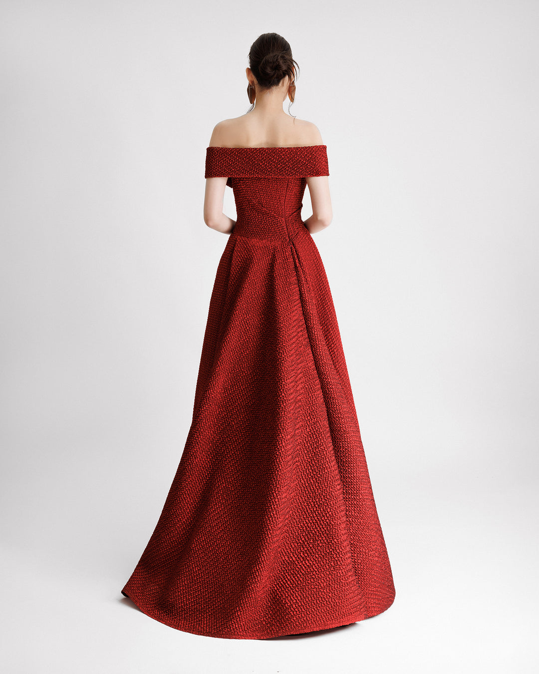 The back of an off-the-shoulders red evening dress with an asymmetrical waistline and draped flared skirt.