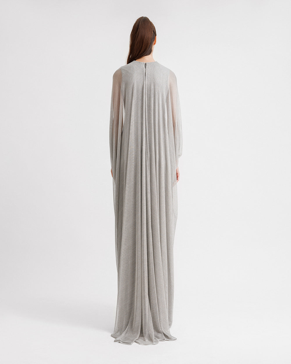 The back of a long silver net tulle evening dress with draping, and cape-like sleeves.