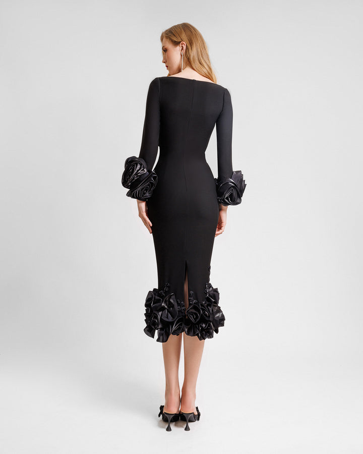 The back of a long sleeved midi dress in black crepe featuring floral cuffs and hemline.