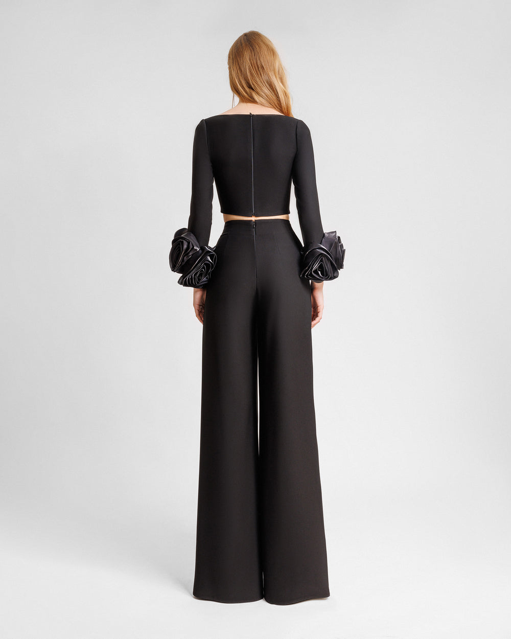 The back of an evening wear set featuring a black top with floral cuffs paired with a straight-cut black pants.