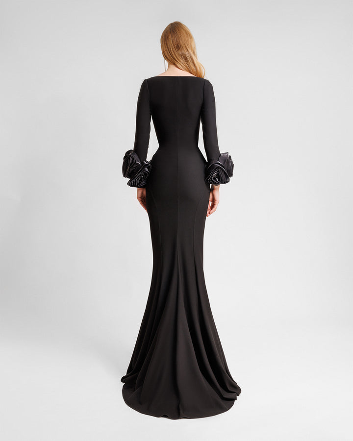 The back of a long sleeved black evening dress in crepe fabric featuring floral cuffs and a slim-cut skirt.