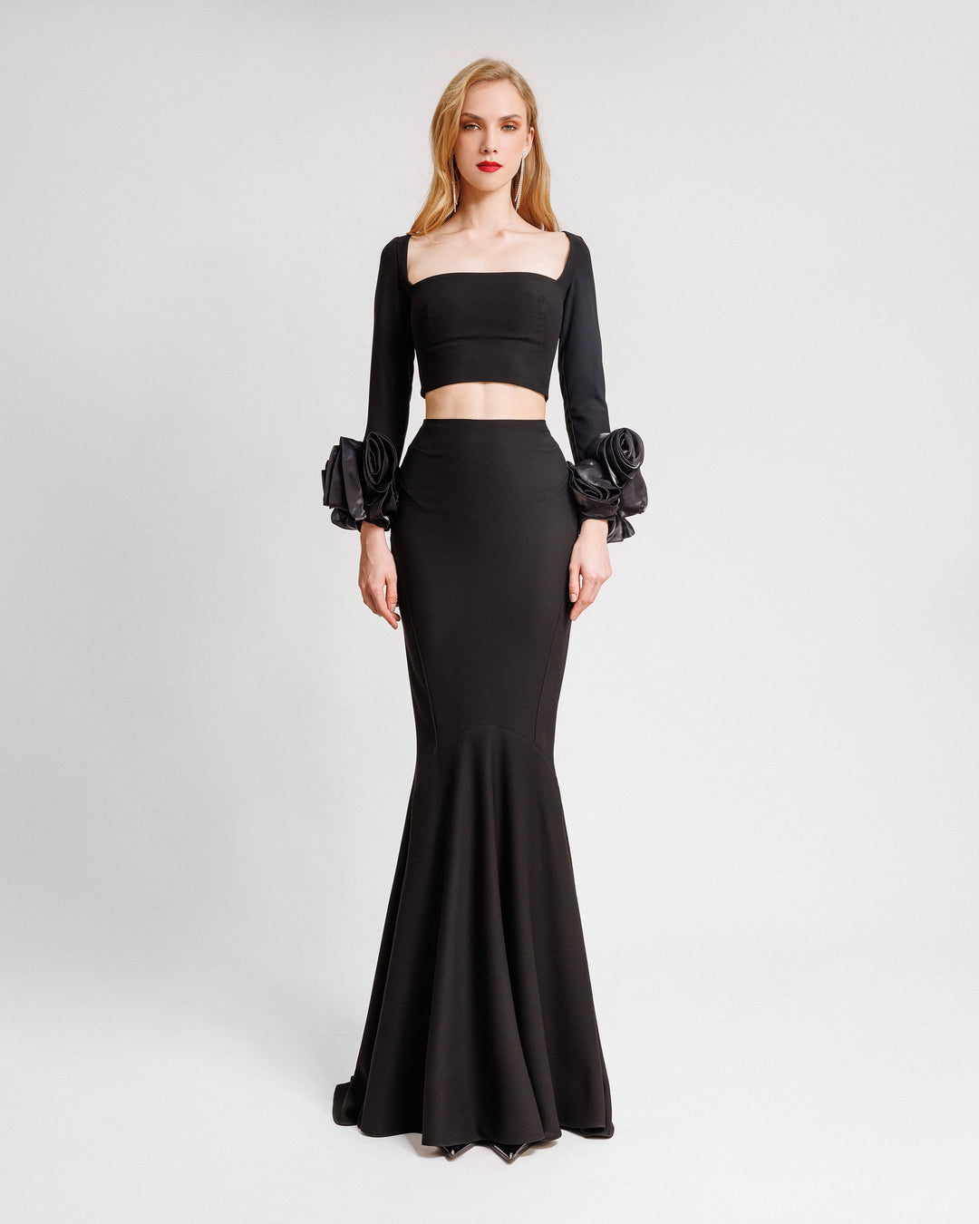 A black evening wear set featuring a squared-neckline crop top with floral cuffs paired with a long slim-cut skirt.