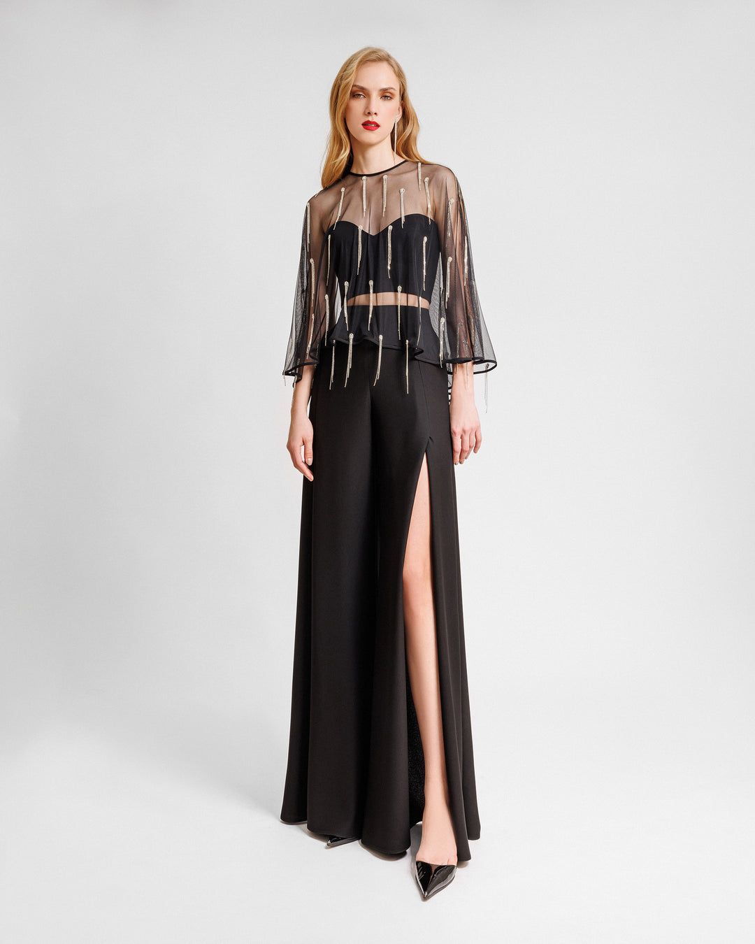 A black evening wear set featuring a tube top with a beaded tulle overlay paired with straight-cut pants with slits on the sides.