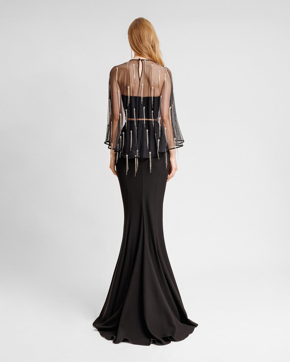 The back of a black evening wear featuring a tube top with a beaded tulle overlay paired with a long slim-cut skirt.