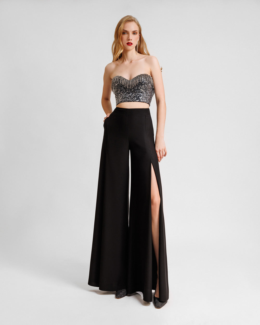 An evening wear set featuring a strapless beaded sequins top paired with a straight-cut black pants with slits on the sides.