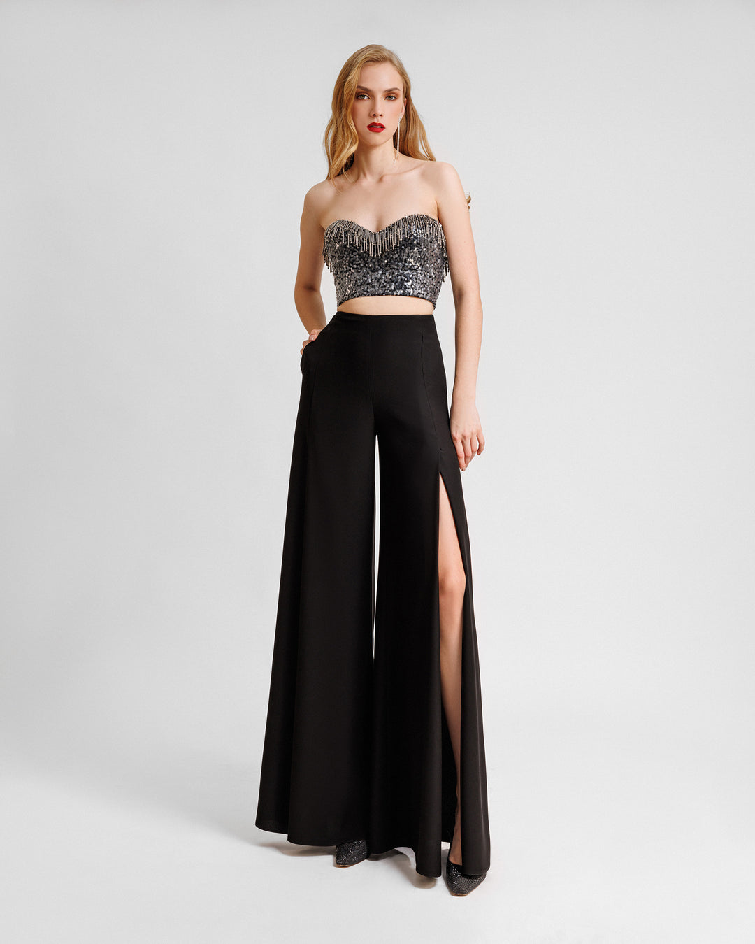 An evening wear set featuring a strapless beaded sequins top paired with a straight-cut black pants with slits on the sides.