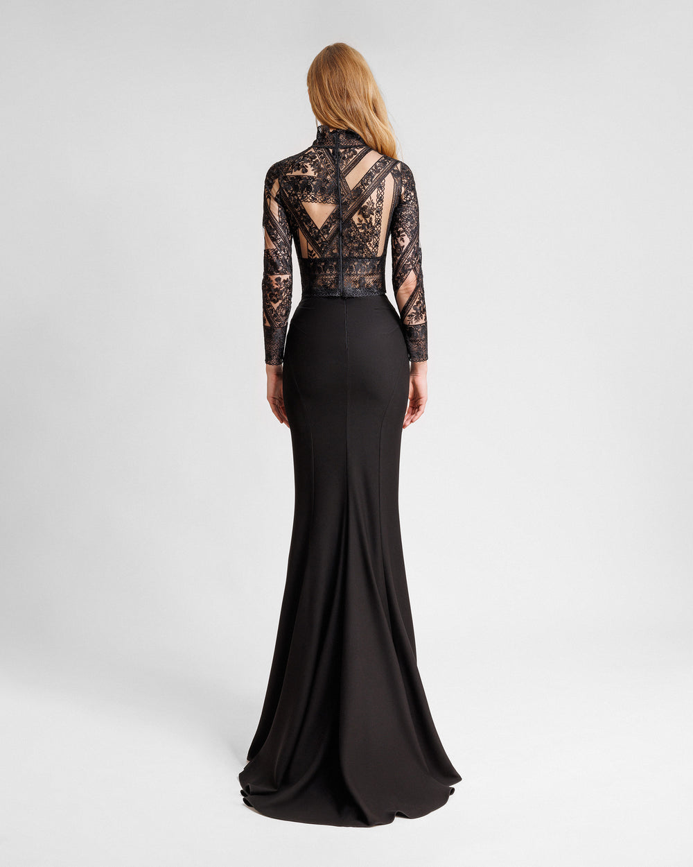 The back of a black evening wear set featuring a long-sleeve patterned lace top paired with a long slim-cut skirt.