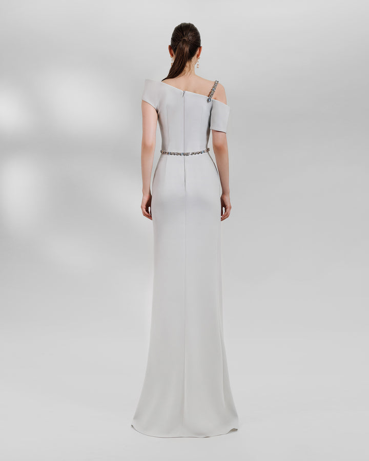 The back of an Asymmetrical neckline grey dress with a beaded strap paired with a draped skirt featuring a slit on the side and a detachable belt.