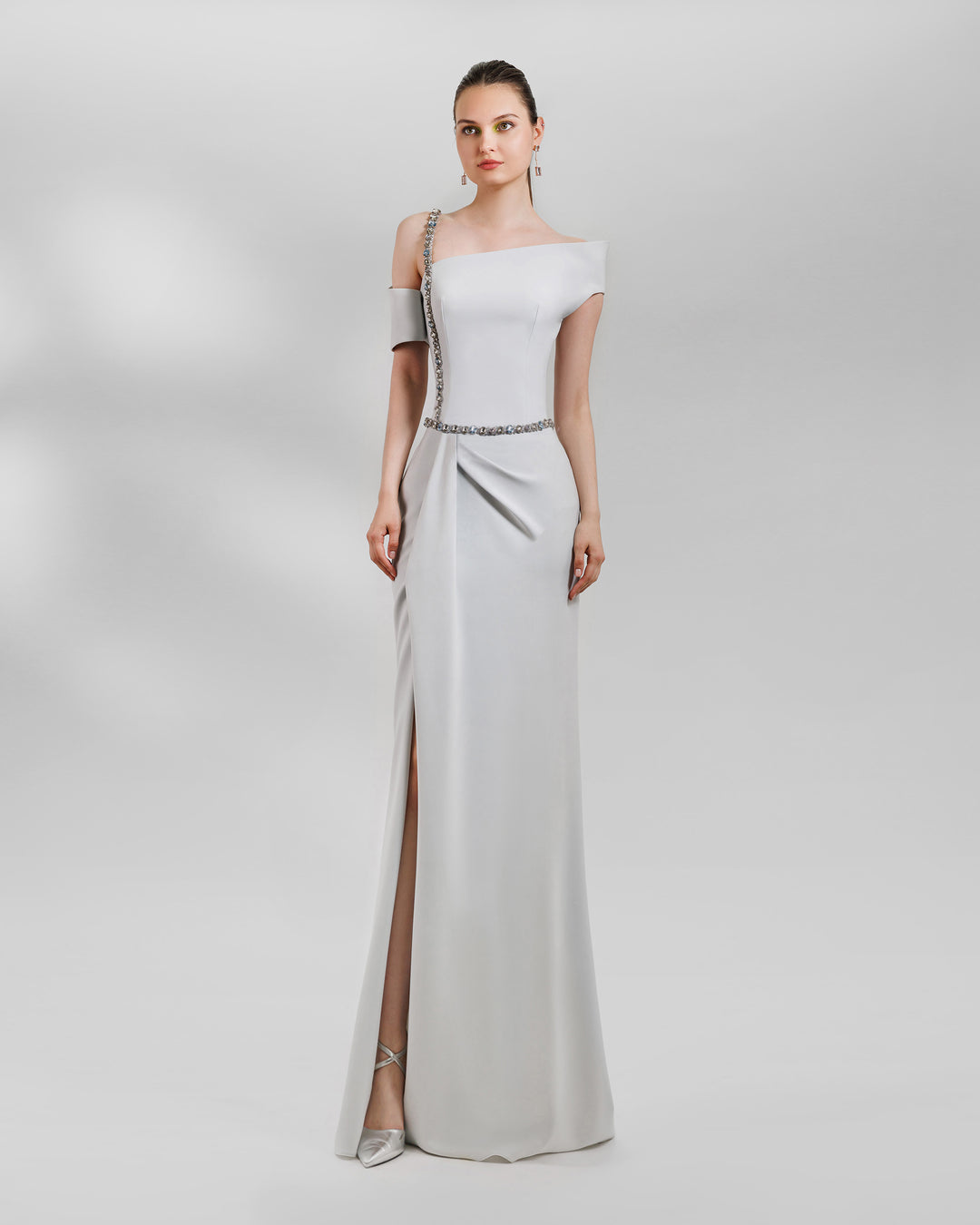 An Asymmetrical neckline grey dress with a beaded strap paired with a draped skirt featuring a slit on the side and a detachable belt.