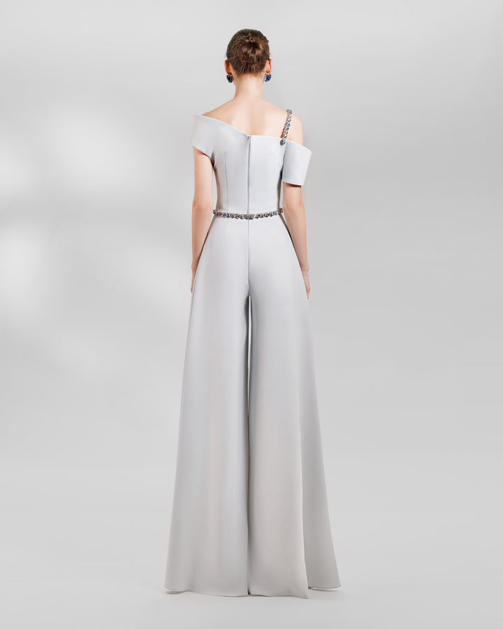 The back of an occasion outfit featuring an asymmetrical neckline grey top with a beaded strap paired a wide high waist grey pants.