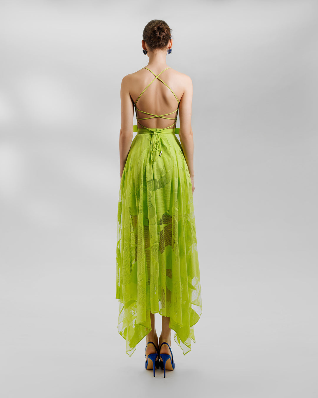 The back of an evening wear set featuring a patterned lace midi skirt with asymmetrical hemline, and a laced open back crepe top, all in lime color.