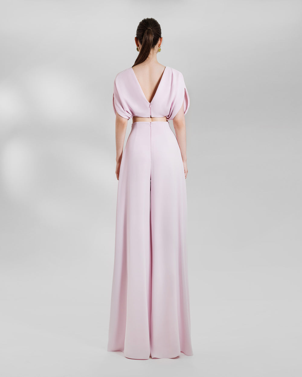 The back of an evening wear pink set featuring a puffed-shoulders, draped cropped top paired with wide high-waist pants.