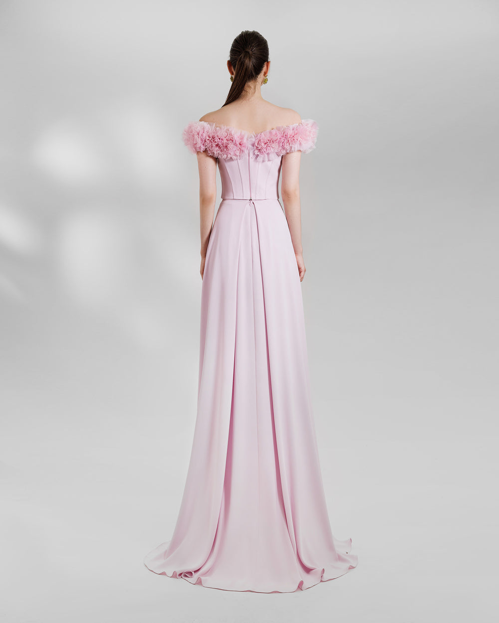 The back of a pink occasion wear featuring an off-the-shoulders corset top with rushed details on the neckline paired with a long skirt.