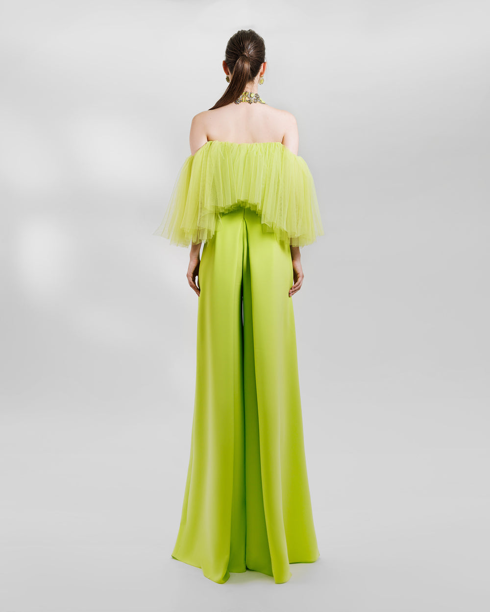 The back of an evening wear lime set featuring an off-the-shoulders tulle top paired with a high-waist wide pants with side pleats. the look is completed with a matching beaded necklace.