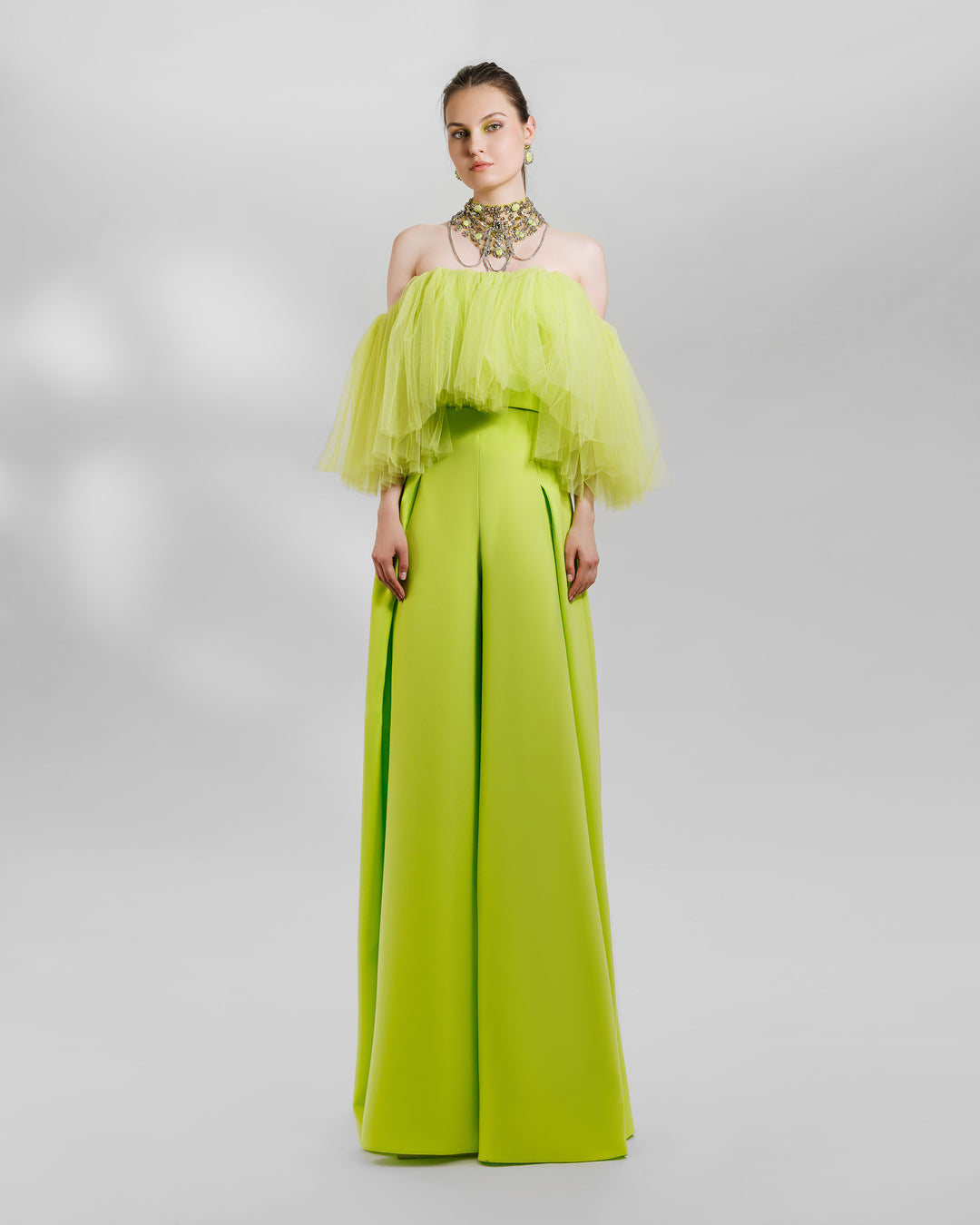 An evening wear lime set featuring an off-the-shoulders tulle top paired with a high-waist wide pants with side pleats. the look is completed with a matching beaded necklace.