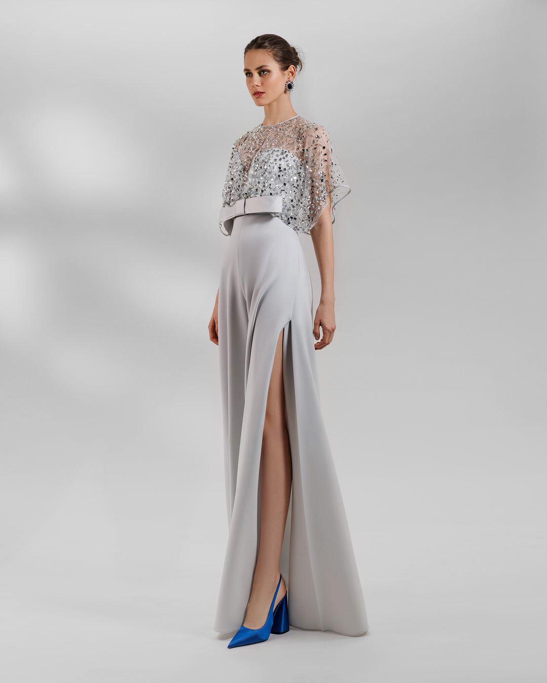 An evening wear grey set featuring a fully beaded top with a crepe bow paired with a high-waist wide pants featuring open slits on the sides.