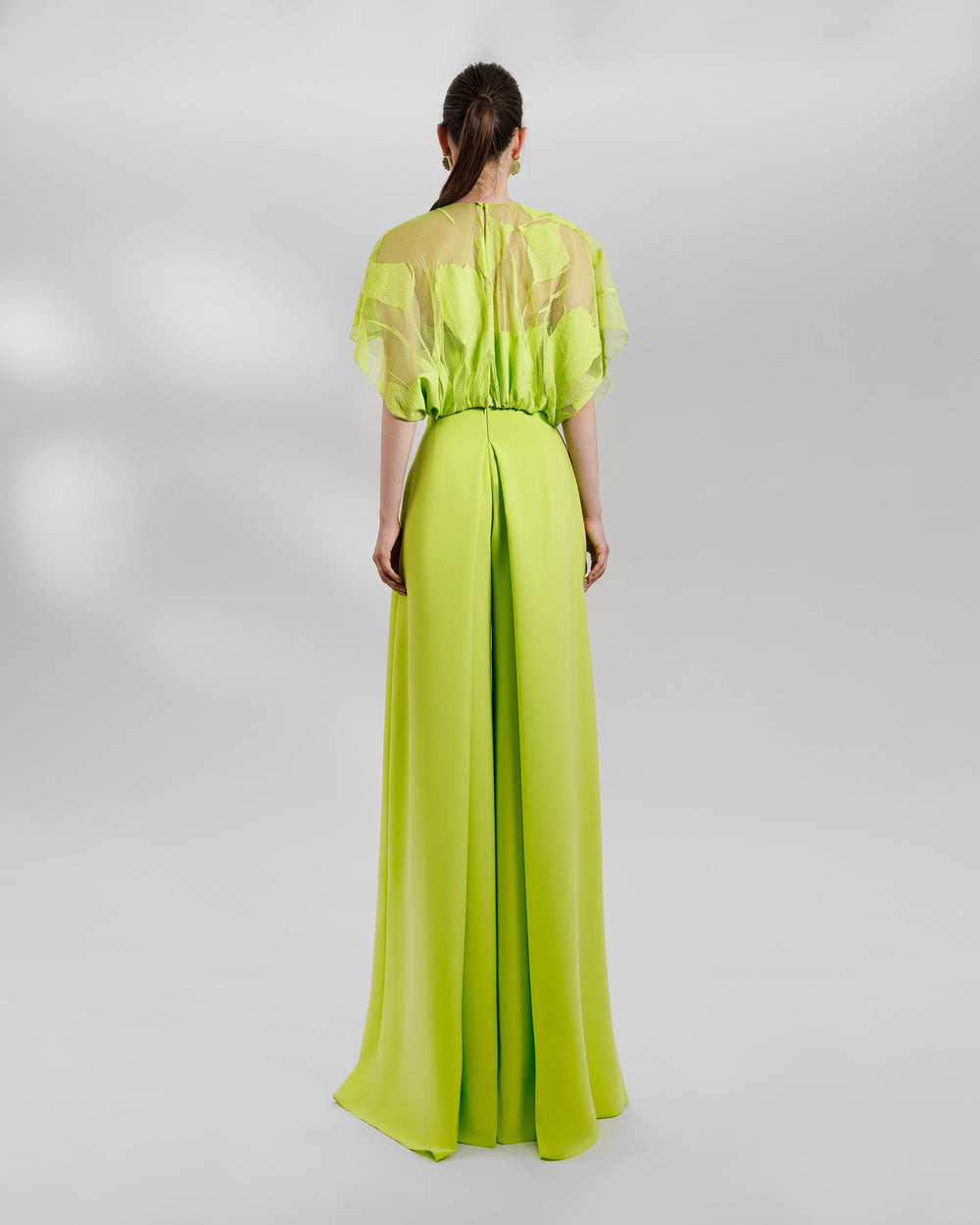 The back of an occasion wear featuring a patterned lace top paired with a high-waist wide pants featuring side pleats, all in lime color.