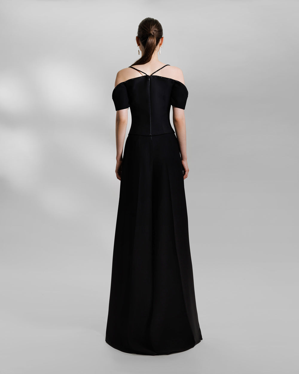 The back of an evening wear black set featuring an off-the-shoulders, sweetheart beaded neckline top paired with wide pants with slits at the front.