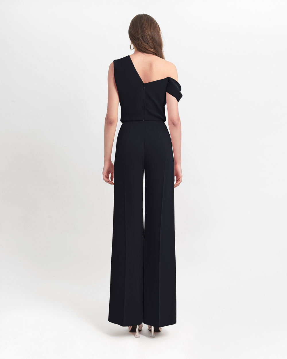 The back of a black evening wear set featuring an asymmetrical cut crepe top with draping details, paired with a straight cut crepe pants.