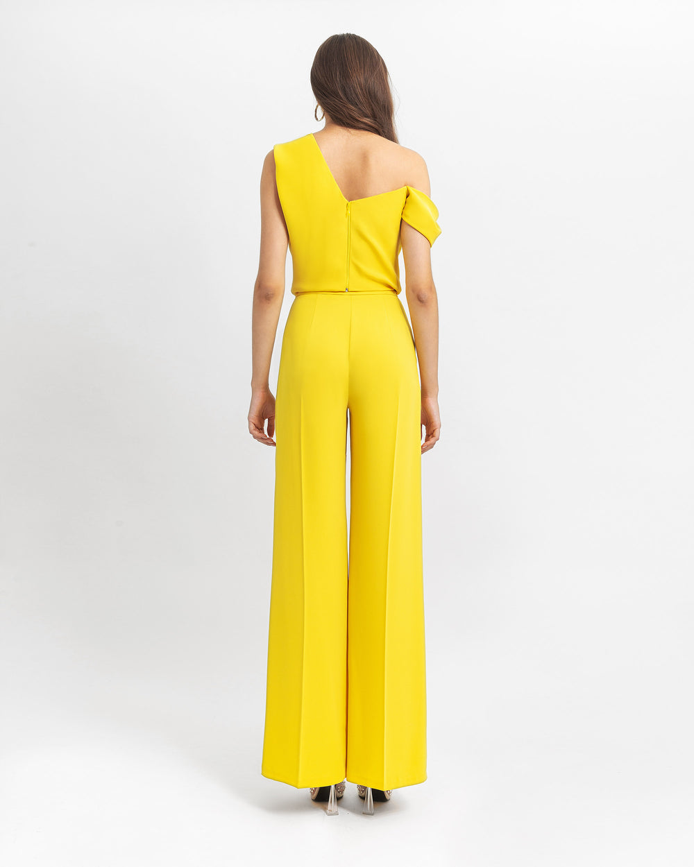 The back of a yellow evening wear set featuring an asymmetrical cut crepe top with draping details, paired with a straight cut crepe pants.