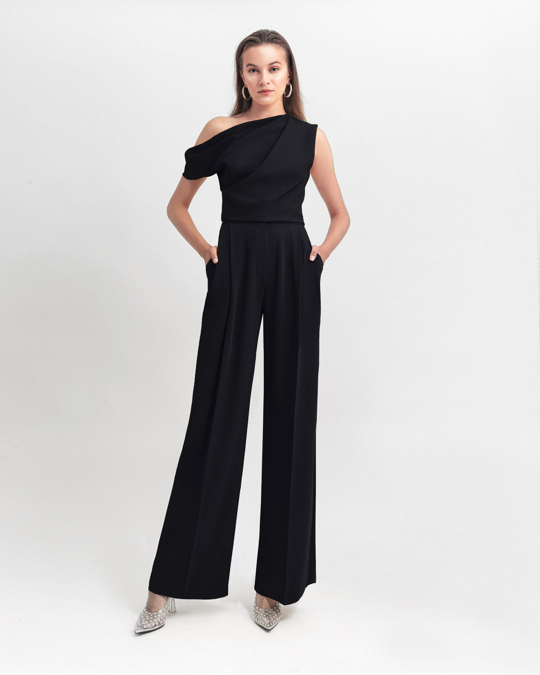 A black evening wear set featuring an asymmetrical cut crepe top with draping details, paired with a straight cut crepe pants.