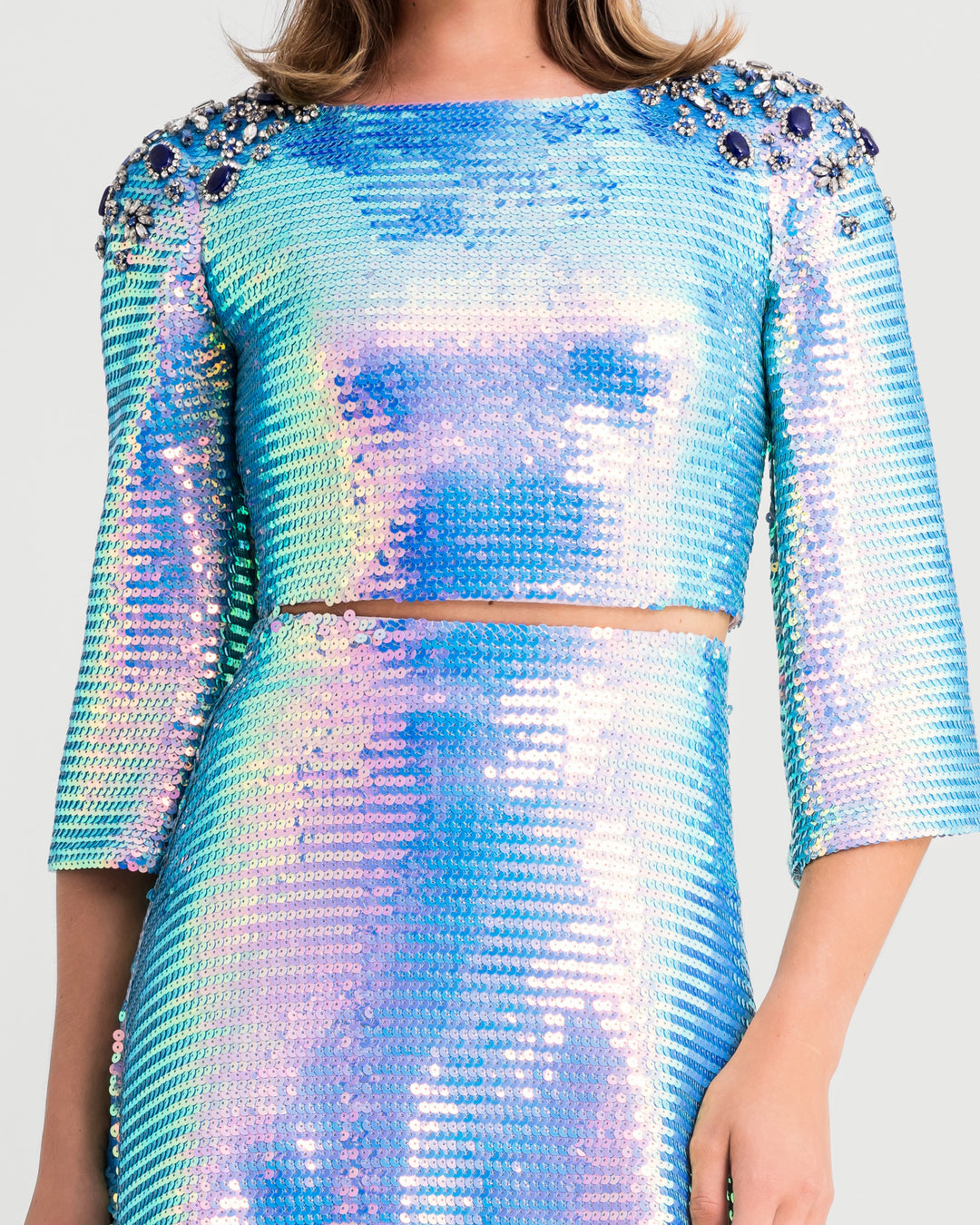 A close-up of a blue sequined evening wear set featuring a sleeved cropped-top with beaded shoulders paired with a flared midi skirt.