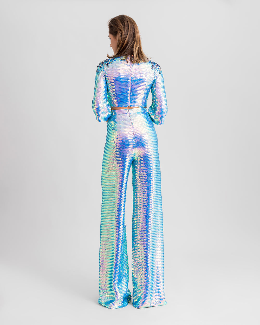 The back of a blue sequined evening wear set featuring a cropped-top with beaded shoulders paired with straight-cut pants.