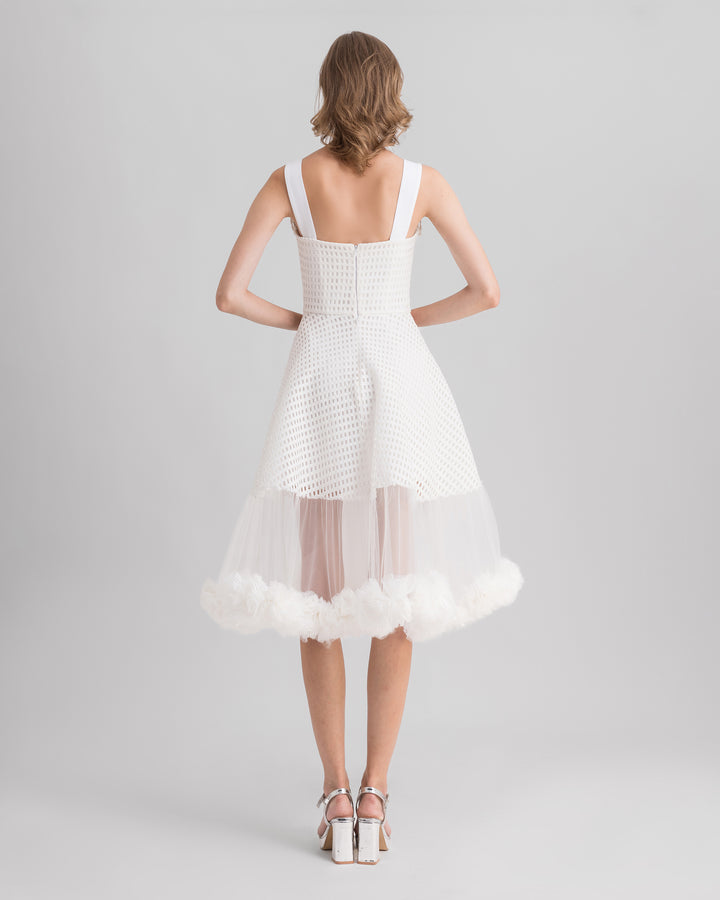 The back of an ivory crochet lace flared midi dress with rushed tulle on the hemline.