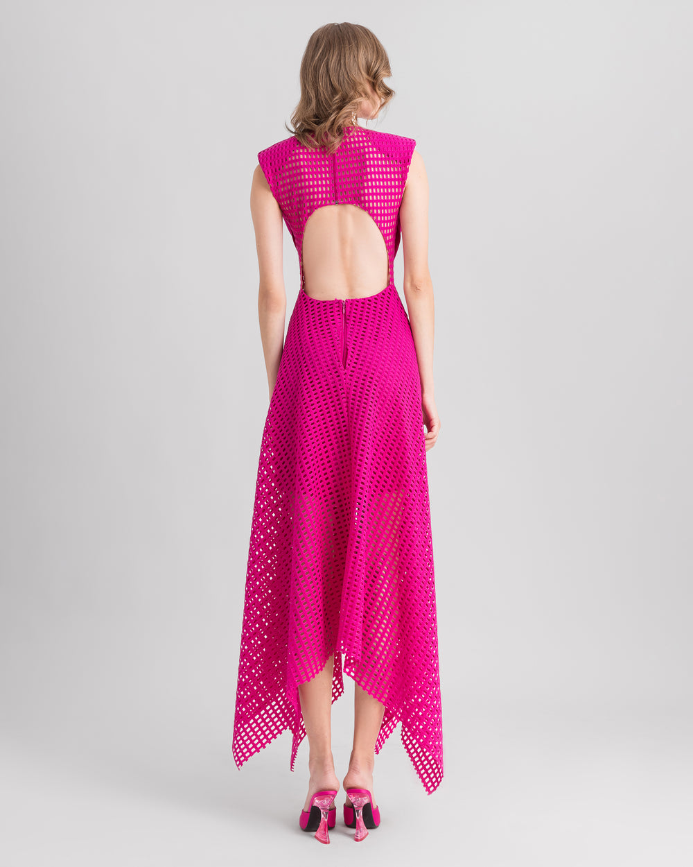 The back of a fuchsia midi dress with an open back and an asymmetrical hemline crochet lace skirt.