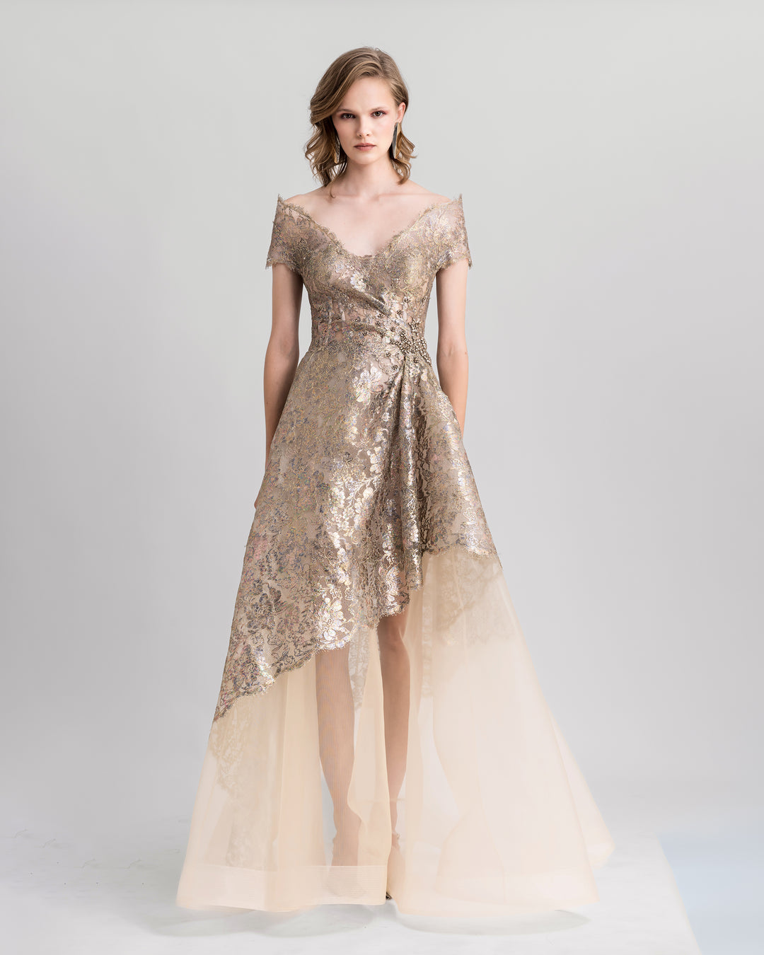 An off-the-shoulders golden evening dress featuring beadings on the waist and an asymmetrical crinoline skirt.